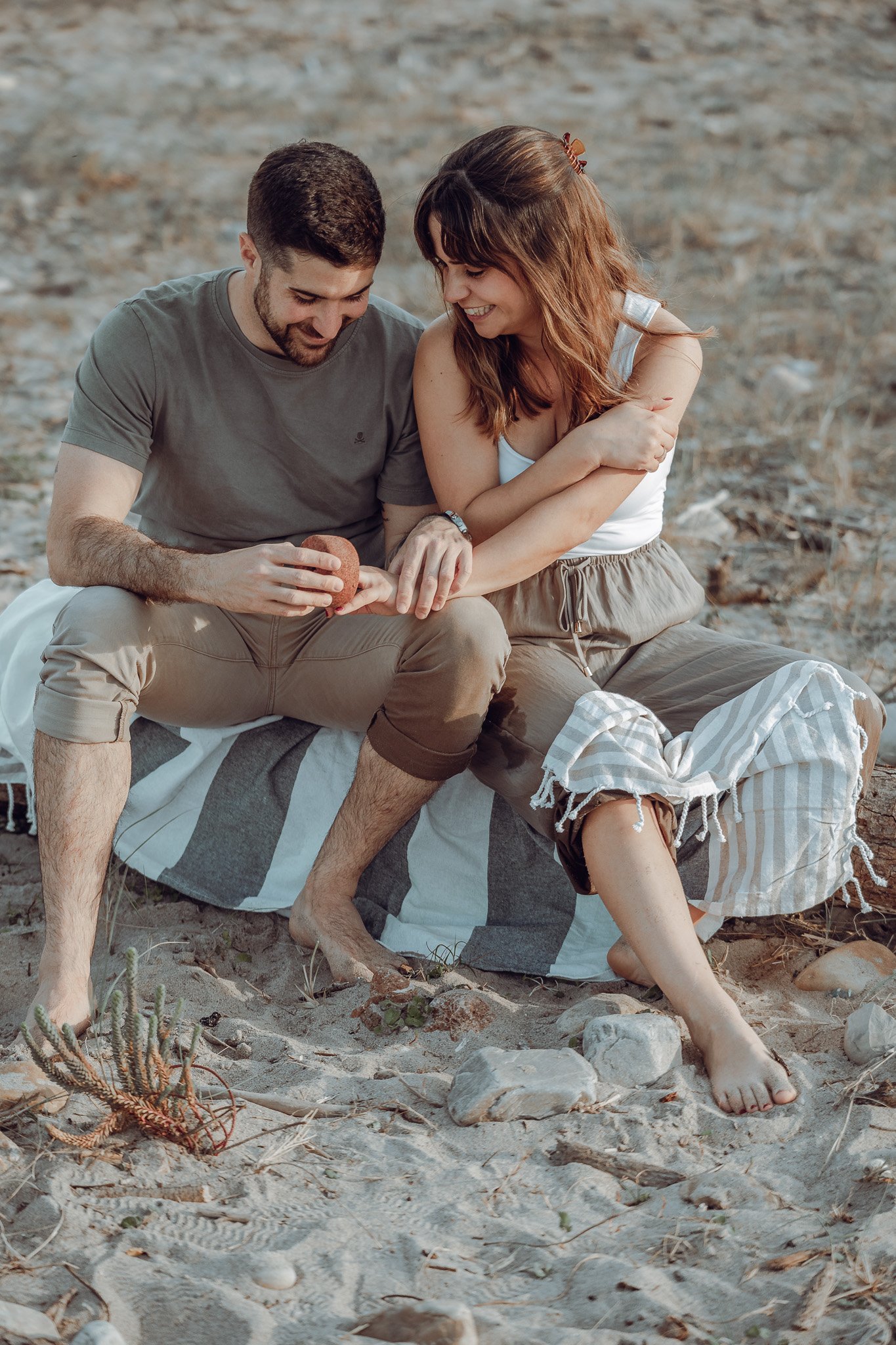 ww_upload_Raquel_y_Aitor_by__wandaweddings-69 Novios sentados en una manta en la playa, riendo, en su sesión de preboda en Asturias